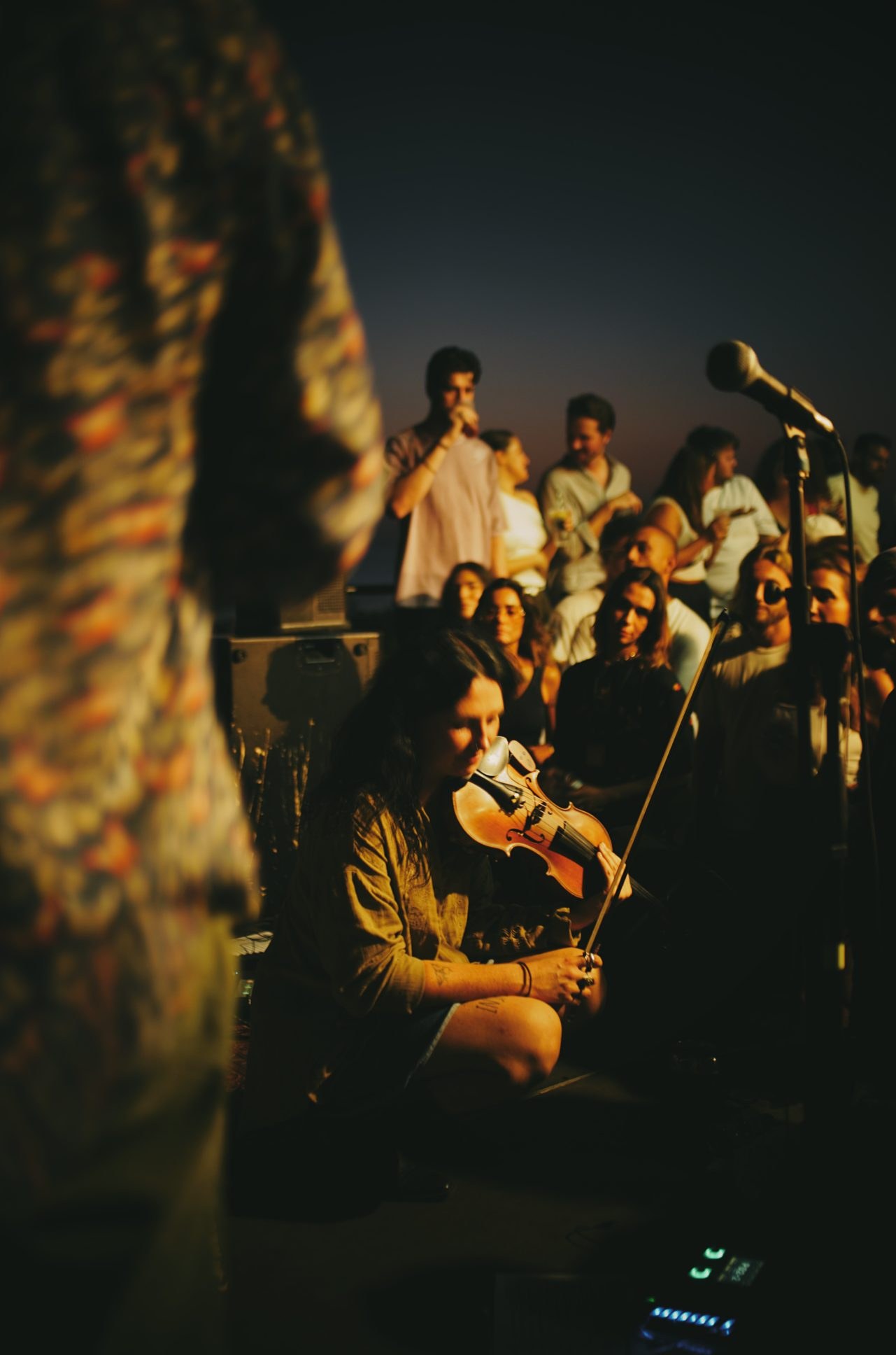 The NEW LIVE band with their instruments on a sea wall at sunset