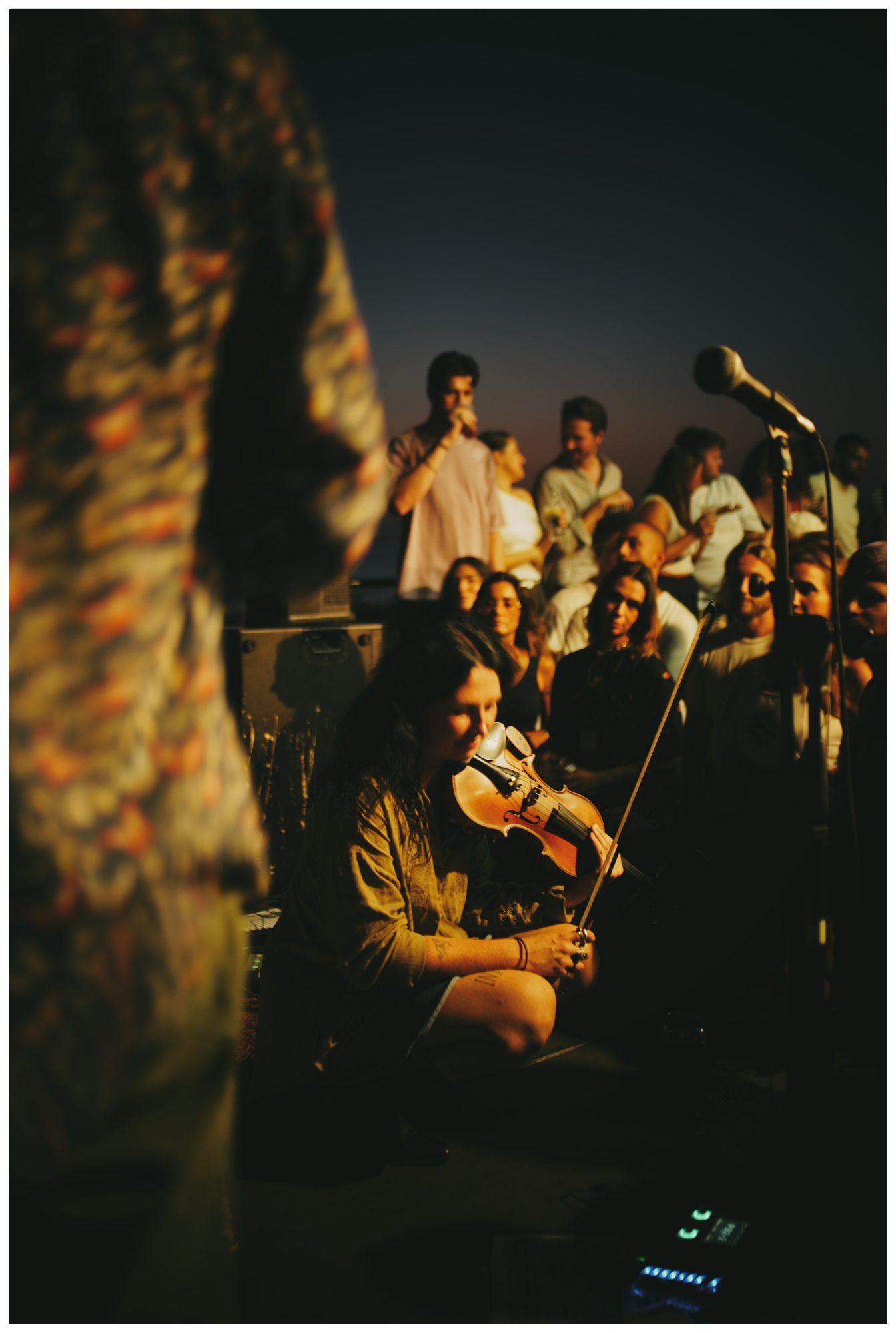 The NEW LIVE band with their instruments on a sea wall at sunset